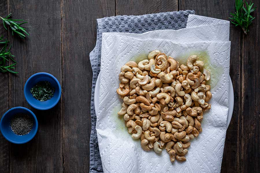 Toasted cashews draining on a paper towel-lined plate to remove oil
