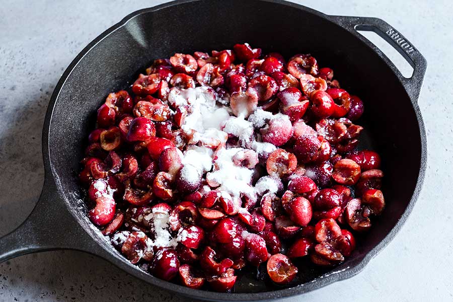 Uncooked cherries in a cast iron skilled with dry ingredients