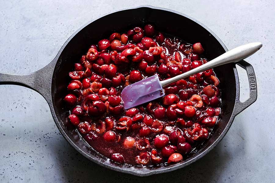 Cooked cherry crumble filling and spatula in a skillet