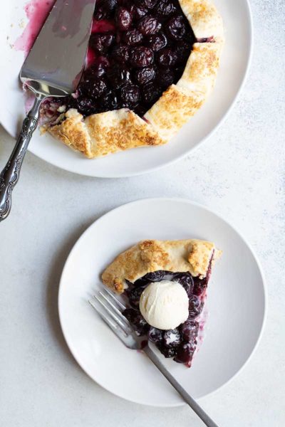 Overhead shot of full cherry galette and a single slice topped with ice cream