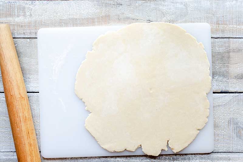 Rolled out tart dough next to rolling pin