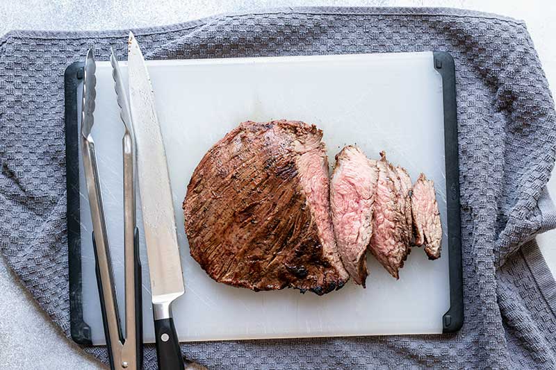 Sliced, grilled flank steak on a cutting board