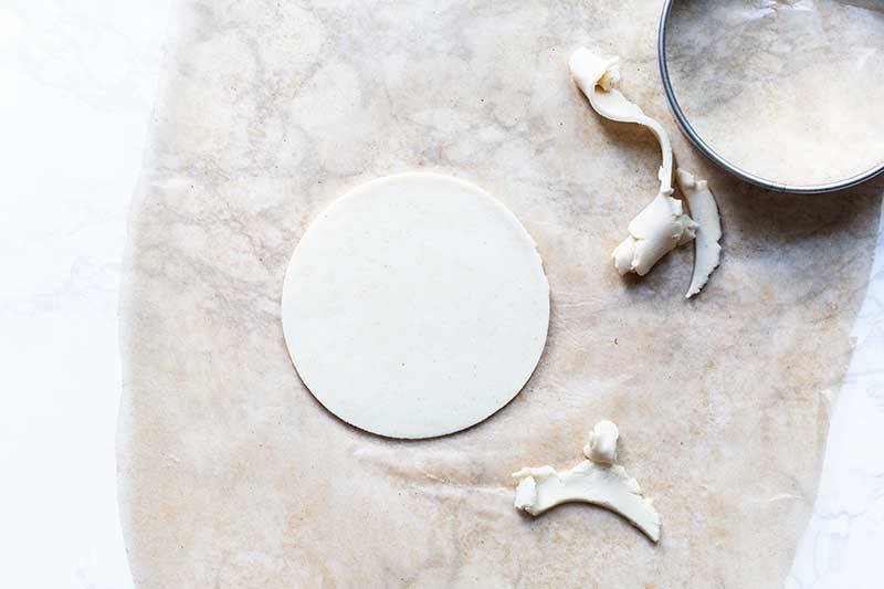 a circle of corn masa dough on wax paper next to excess dough