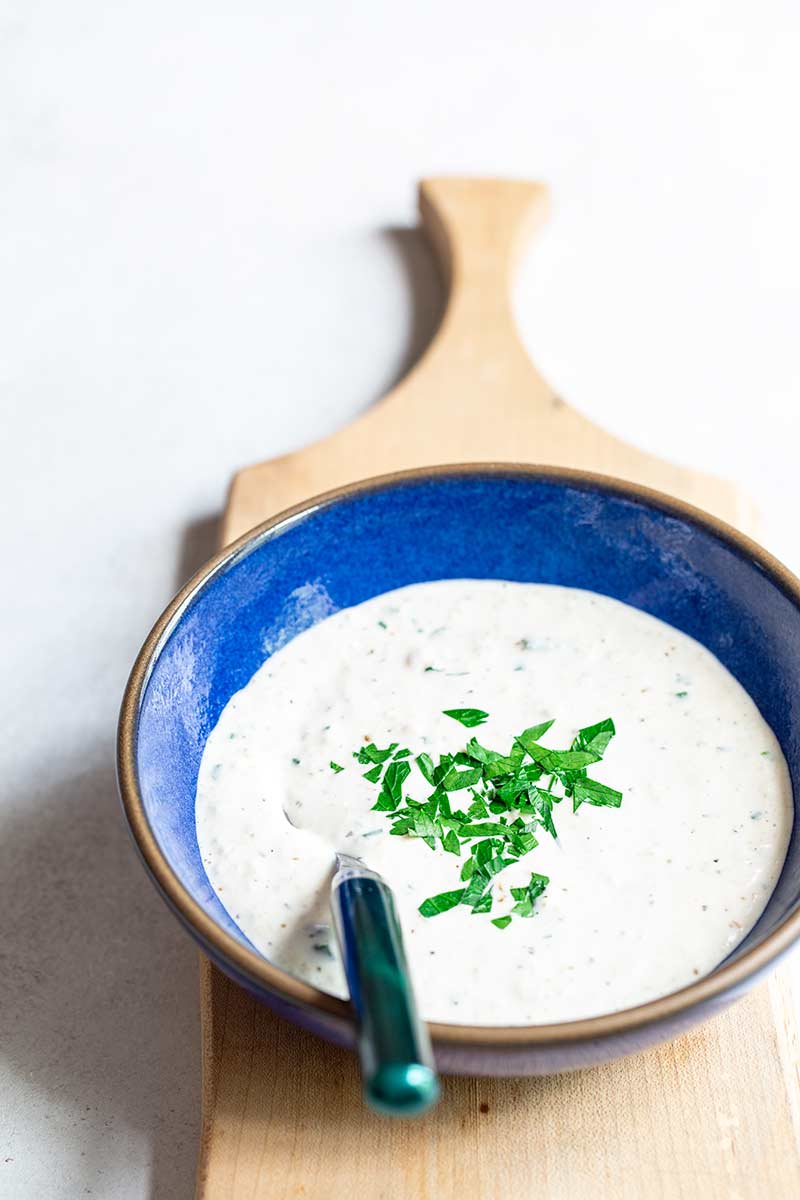 homemade horseradish sauce topped with fresh parsley, in a blue bowl