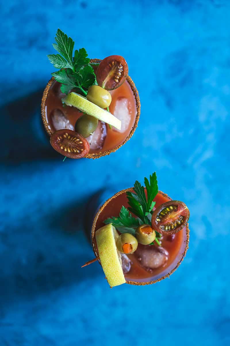 Overhead shot of a tomato juice and vodka cocktail with vegetable garnishes in the glass