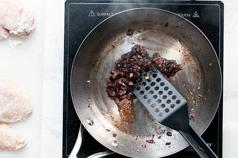 Reducing the wine while a spatula stirs the shallots