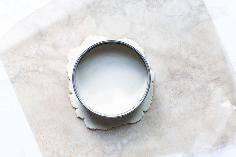 a round biscuit cutter pressing into the rolled corn tortilla dough