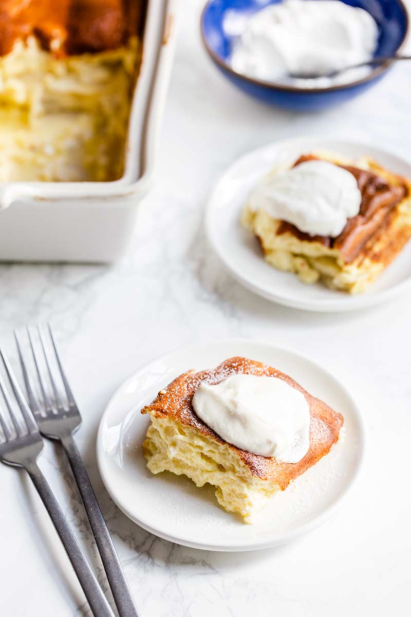 close up of blintz souffle on a plate topped with sour cream and sugar