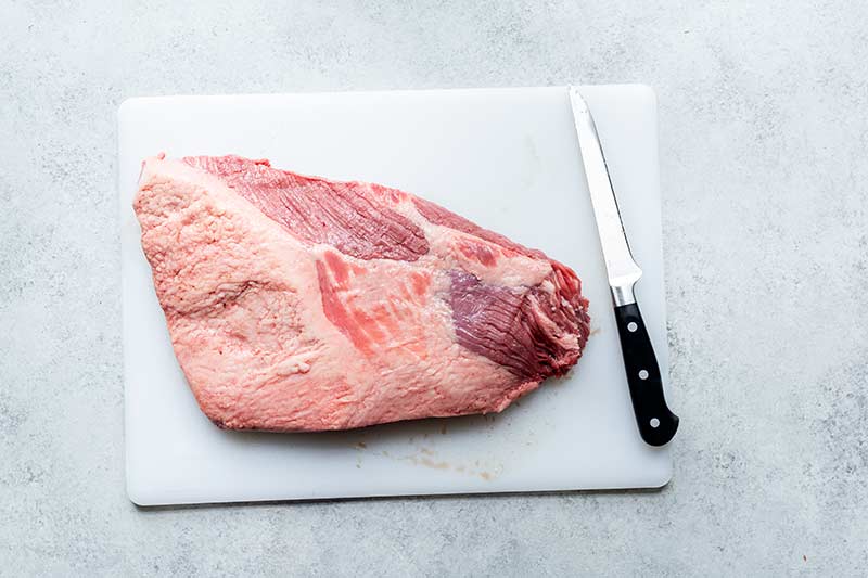 large cut of beef on cutting board with a boning knife next to it
