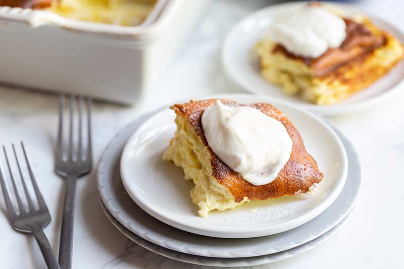 close up of a single serving of blintz souffle on a plate topped with sour cream and sugar