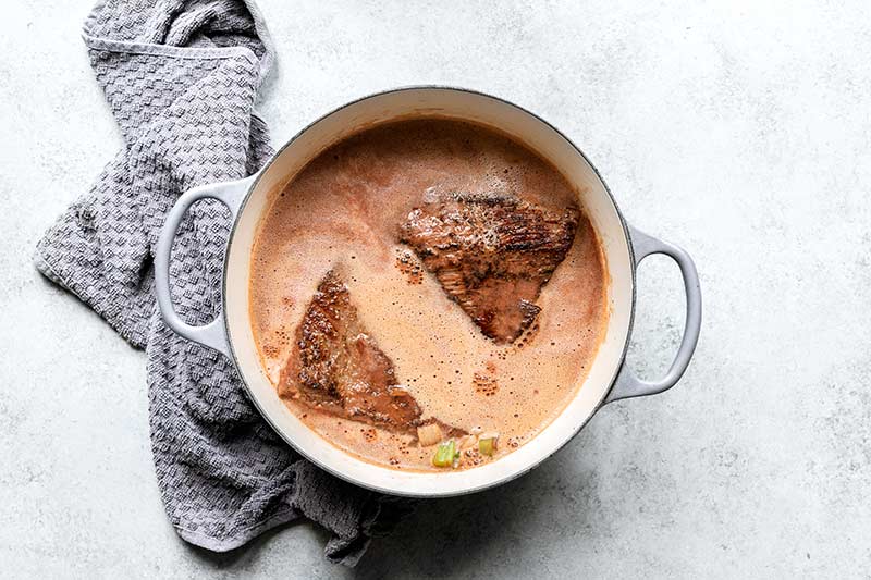 Liquid ingredients added to dutch oven along with beef brisket