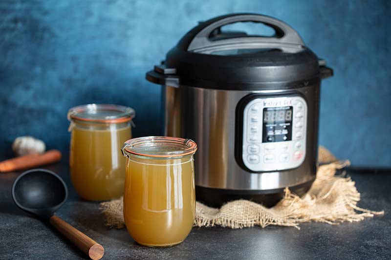 Pressure cooker chicken stock in mason jars in front of an Instant Pot