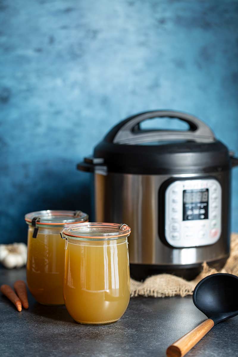 Chicken stock in two large mason jars in front of an Instant Pot pressure cooker