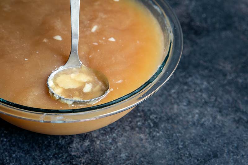 A bowl of chilled stock with a ladle skimming off the fat