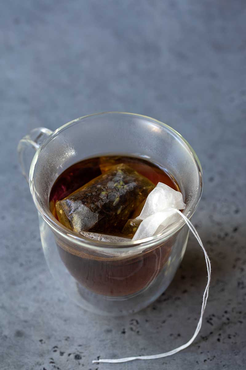 tea bag in clear mug brewing with hot water