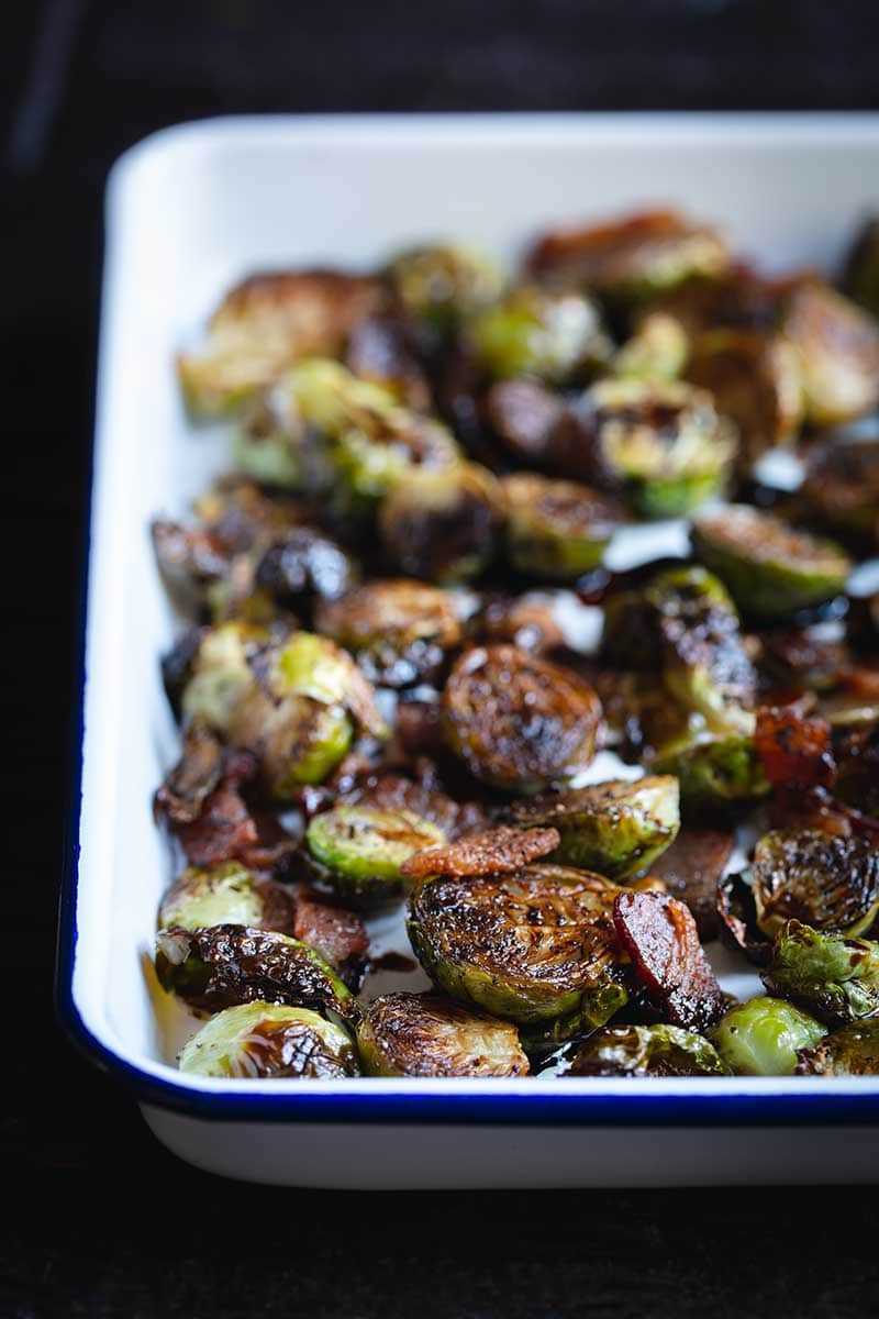 Roasted balsamic bacon Brussels Sprouts in a white serving pan.