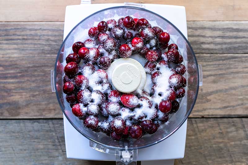 cranberries and sugar in the bowl of a food processor