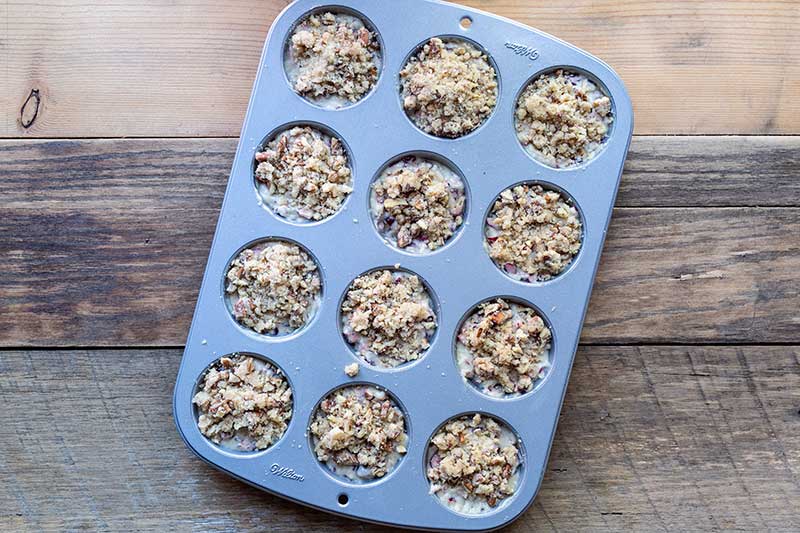 Muffin batter divided into muffin pan with streusel topping on top