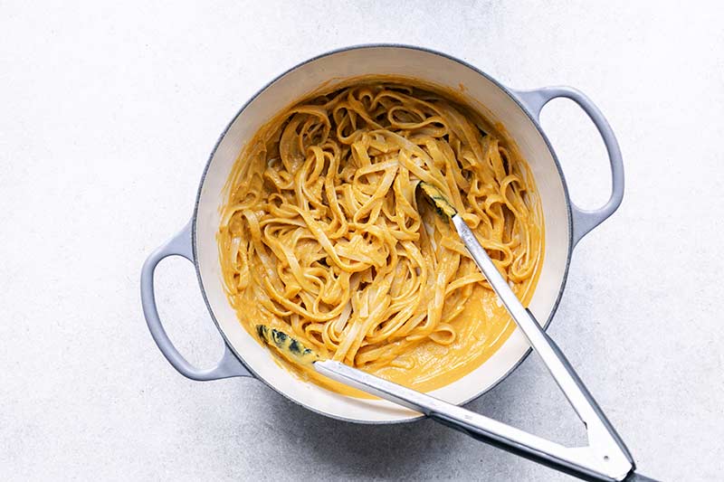 Homemade pumpkin sauce being tossed with linguini