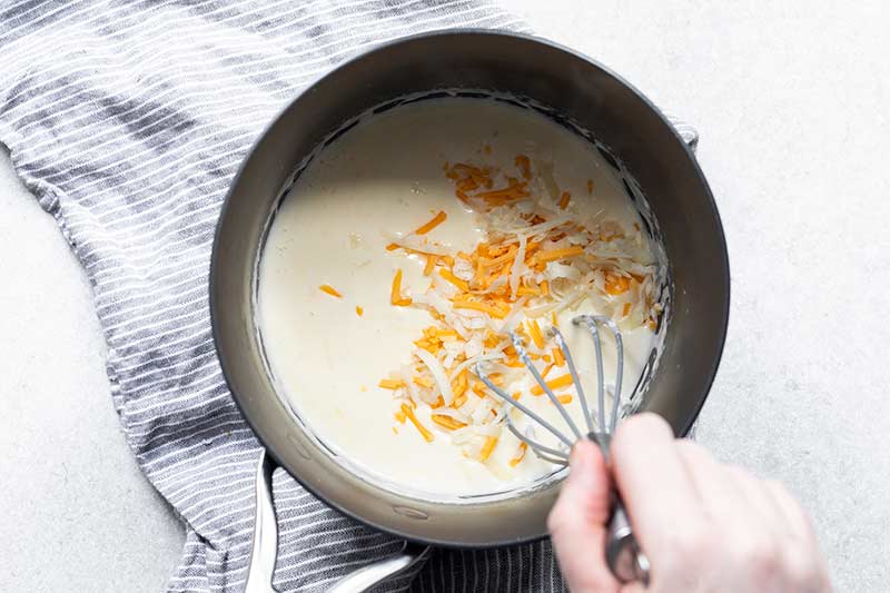 Whisking cheese into béchamel sauce 