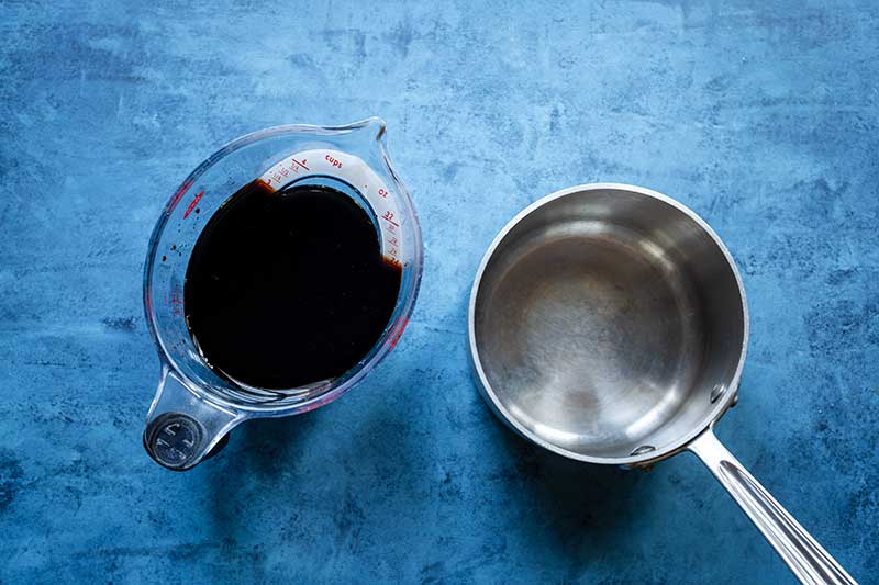 3 cups of balsamic vinegar in liquid measuring cup next to saucepan