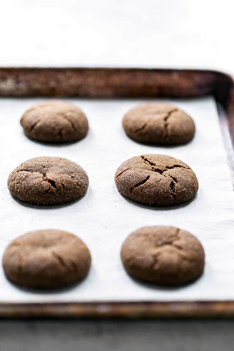 Side angle of freshly baked soft molasses cookies on a sheet pan