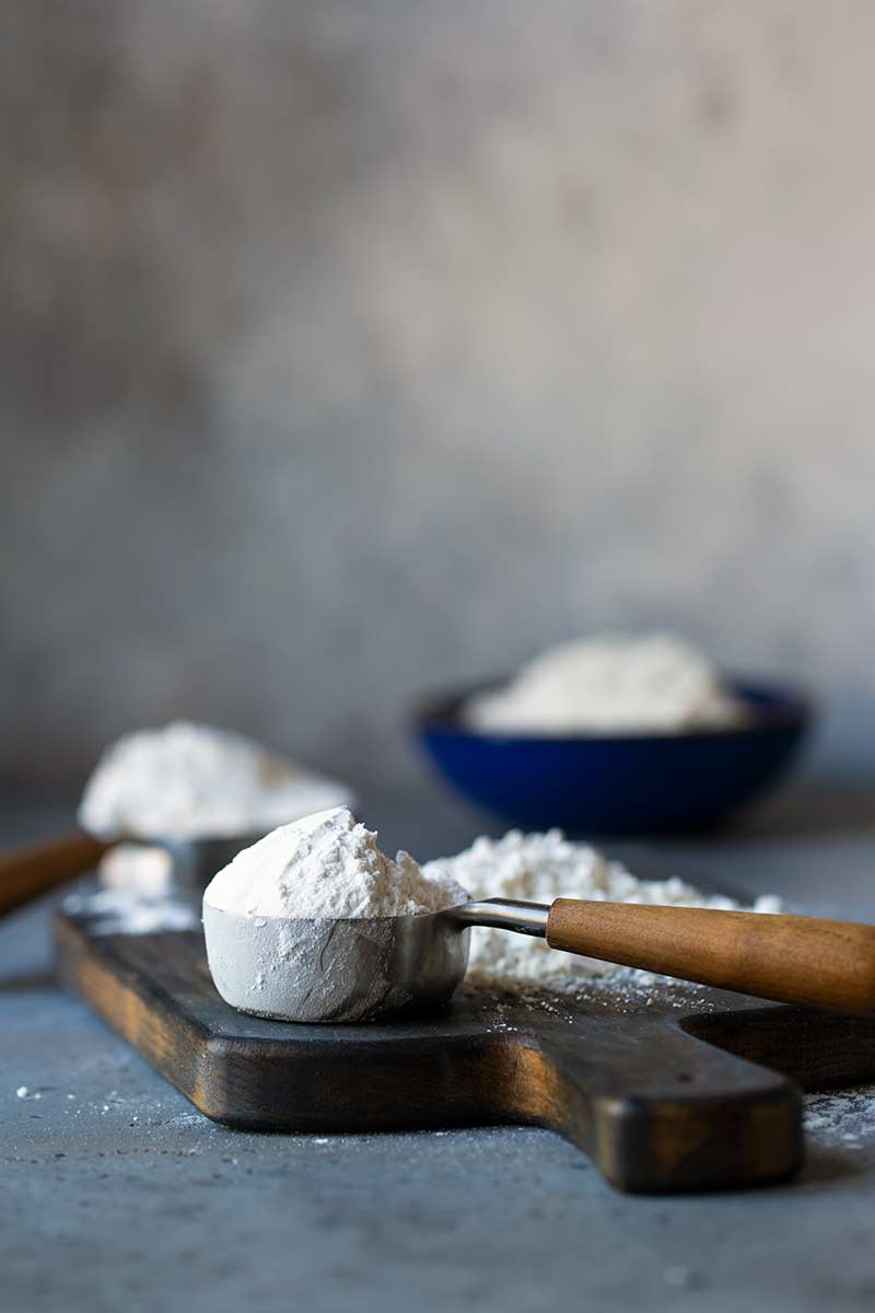 Different types of flour displayed in bowls and measuring cups