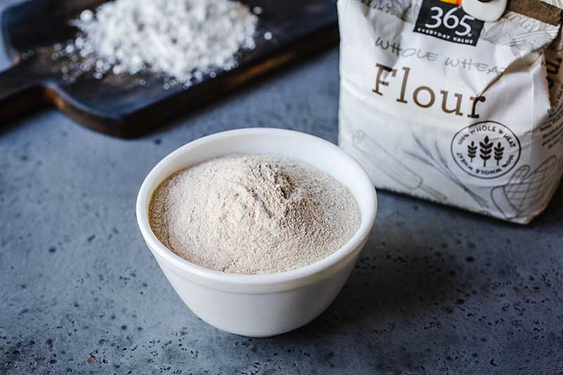 whole wheat flour in a bowl next to the package