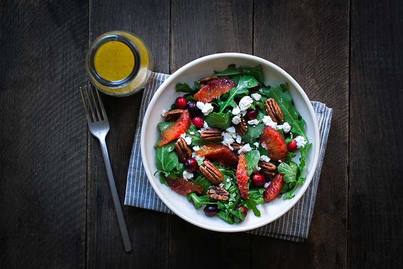 Finished salad next to bottle of orange vinaigrette