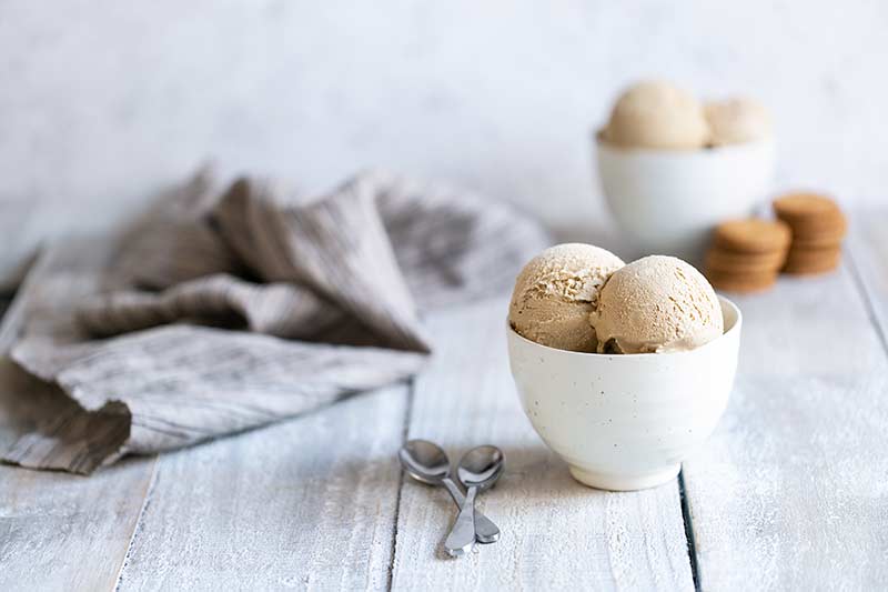 Gingerbread ice cream recipe served in bowls next to spoons an gingersnap cookies