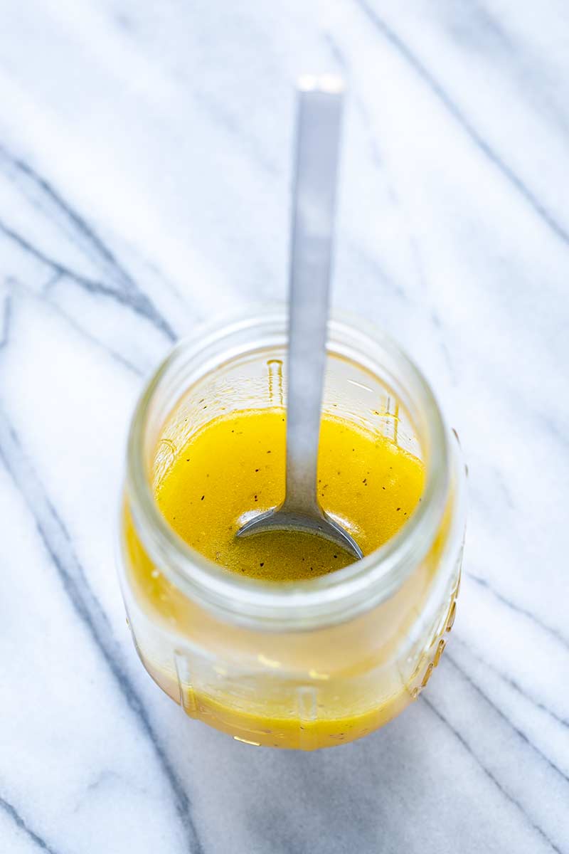 orange vinaigrette in a mason jar with a spoon