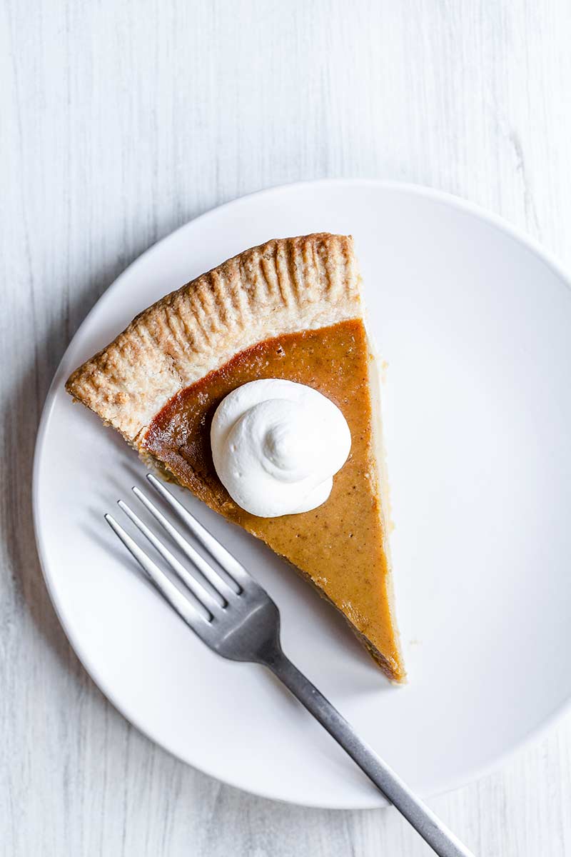 A slice of homemade pumpkin pie topped with whipped cream