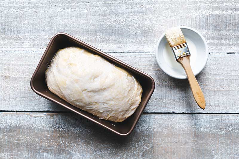 Dough that has risen in loaf pan, brushed with cream