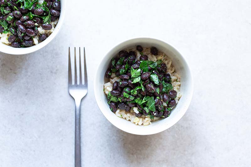 Black beans and rice recipe in a bowl next to a fork.