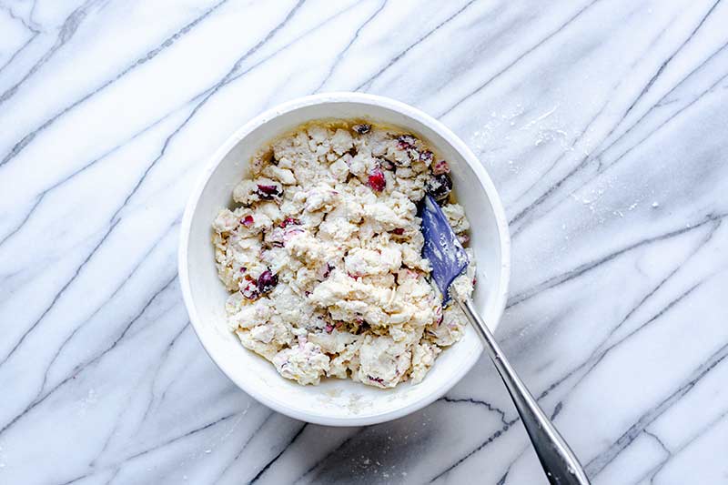 A spatula stirring wet and dry scone ingredients together.