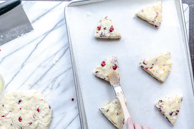Brushing raw scones with butter.