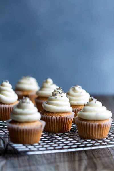 Six London fog cupcakes on a cooling rack, topped with lavender.