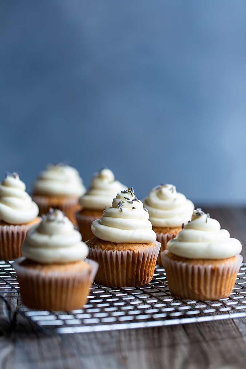 Six London fog cupcakes on a cooling rack, topped with lavender.