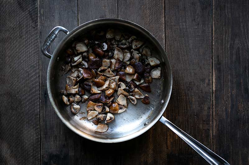 Sautéing mushrooms in a flat-sided skillet until brown.