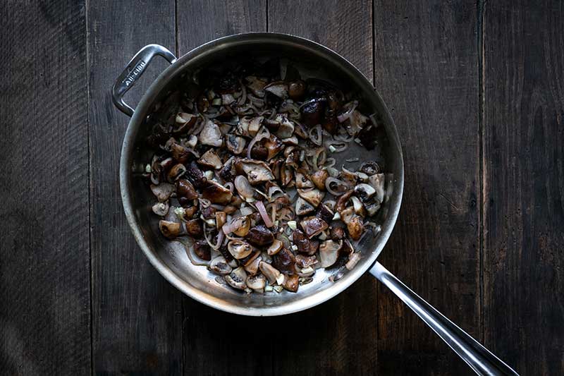 Sautéing shallots alongside the mushrooms.