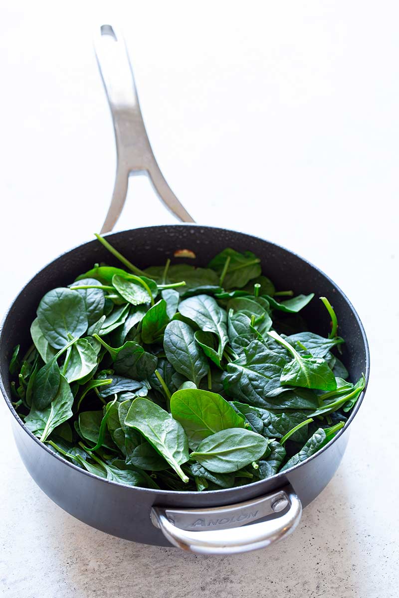 Spinach added to the skillet, all the way to the top.