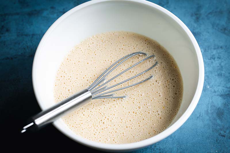 Wet ingredients in a bowl with a whisk