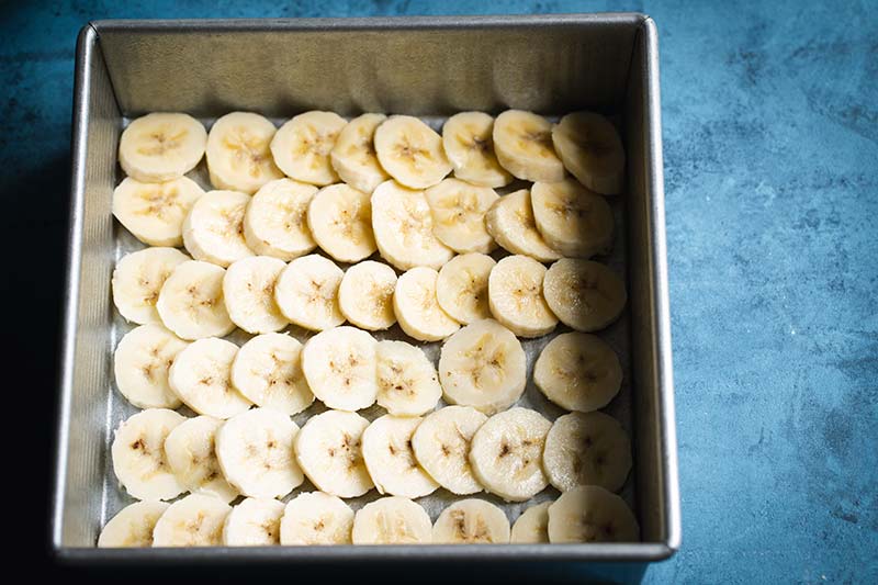 A layer of sliced bananas on the bottom of an 8x8 pan