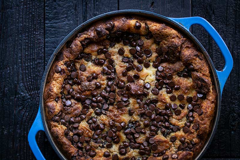 Croissant bread pudding in a round blue baking dish.