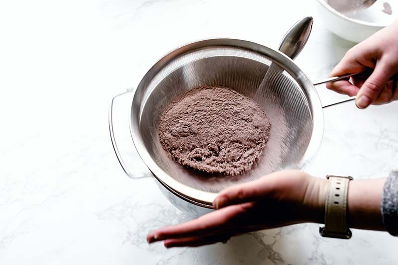 Sifting dry ingredients together through a fine mesh strainer