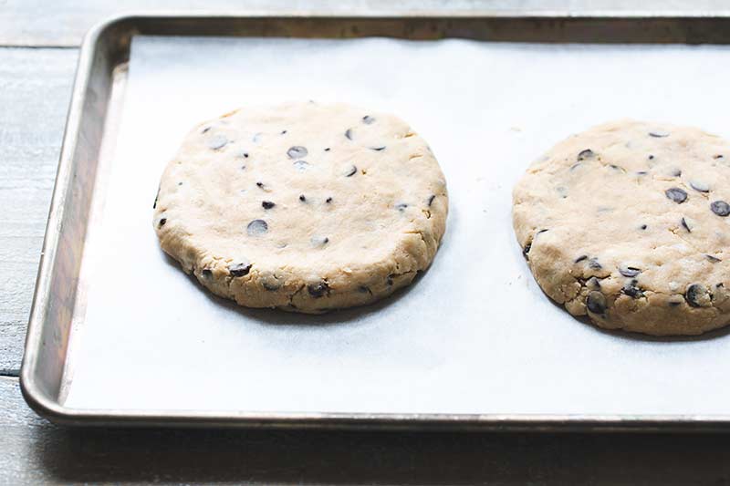 Dough formed into two round discs on a sheet pan lined with parchment