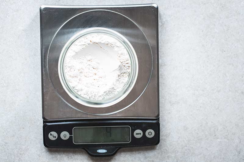 Flour measured out in a jar set on a digital scale