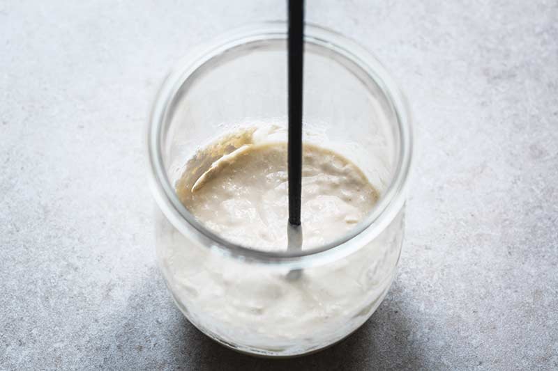 Smooth dough mixed together from flour and water in a jar with a chopstick