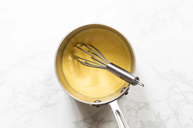 a saucepan with egg yolks and sugar whisked together