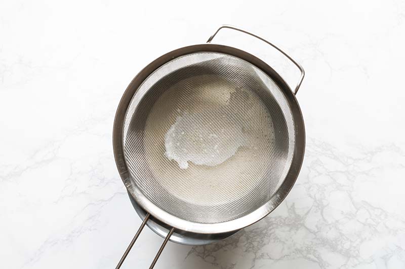 Cooked gelato base strained through a fine mesh strainer to remove lumps